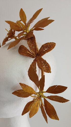 A picture of a gold feather flower headband by Melissa Rath Millinery.