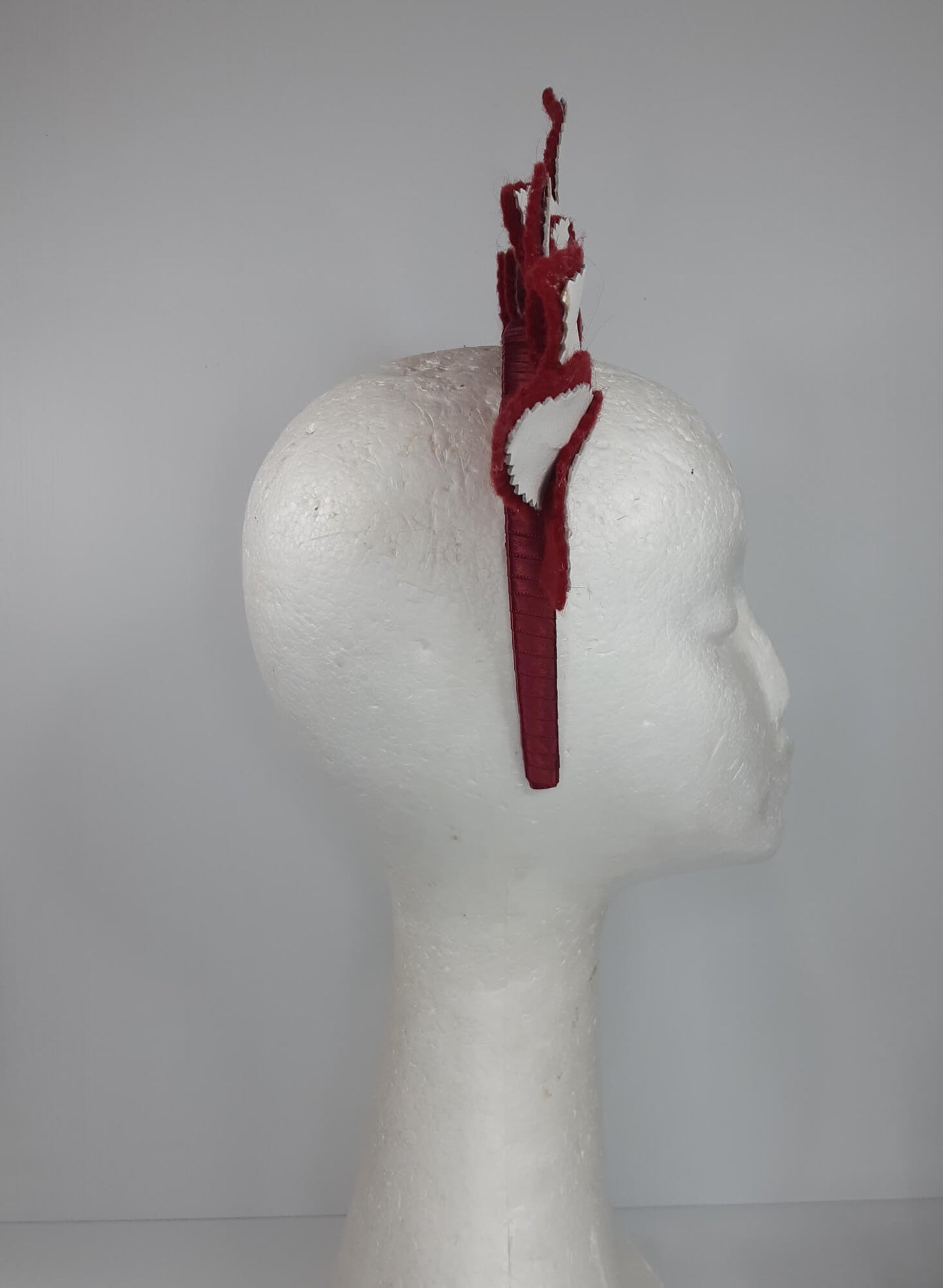 A picture of a red and white leather headband by Melissa Rath Millinery