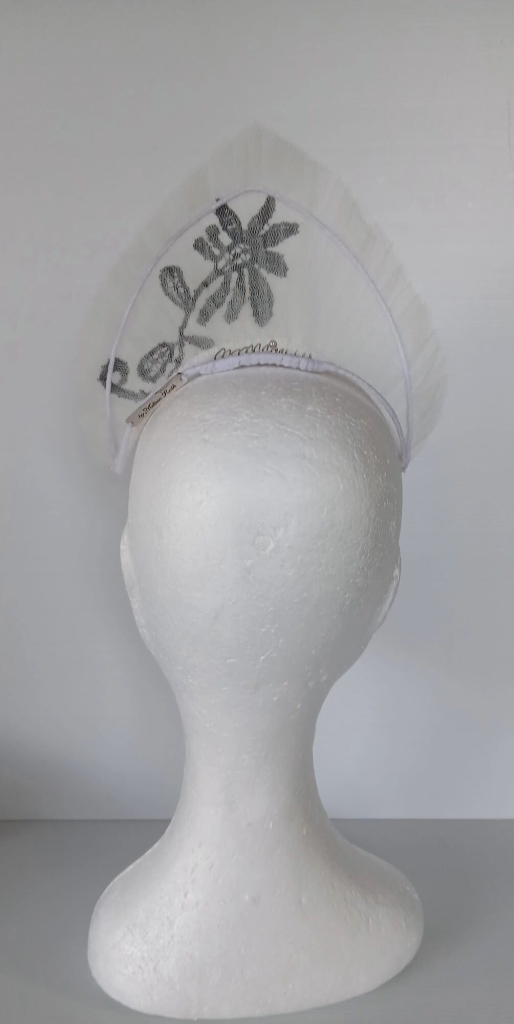 A picture of a white tulle crown by Melissa Rath Millinery.