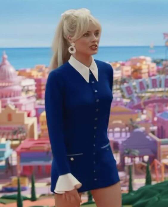 A picture of Margot Robbie as Barbie in a navy mini dress with a white collar and cuffs.