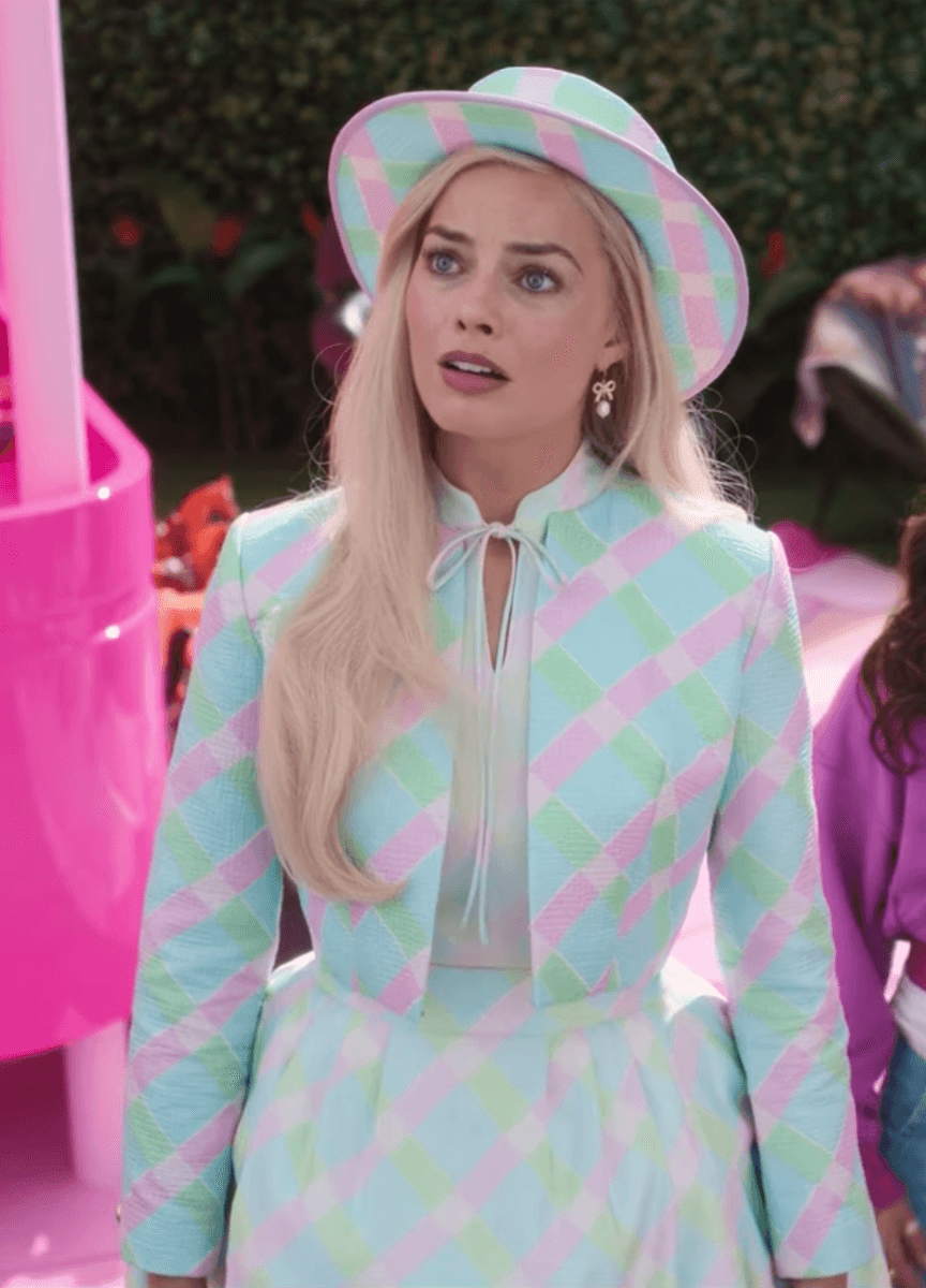 A picture of Margot Robbie as Barbie in a pink , green and blue suit and matching sun hat.