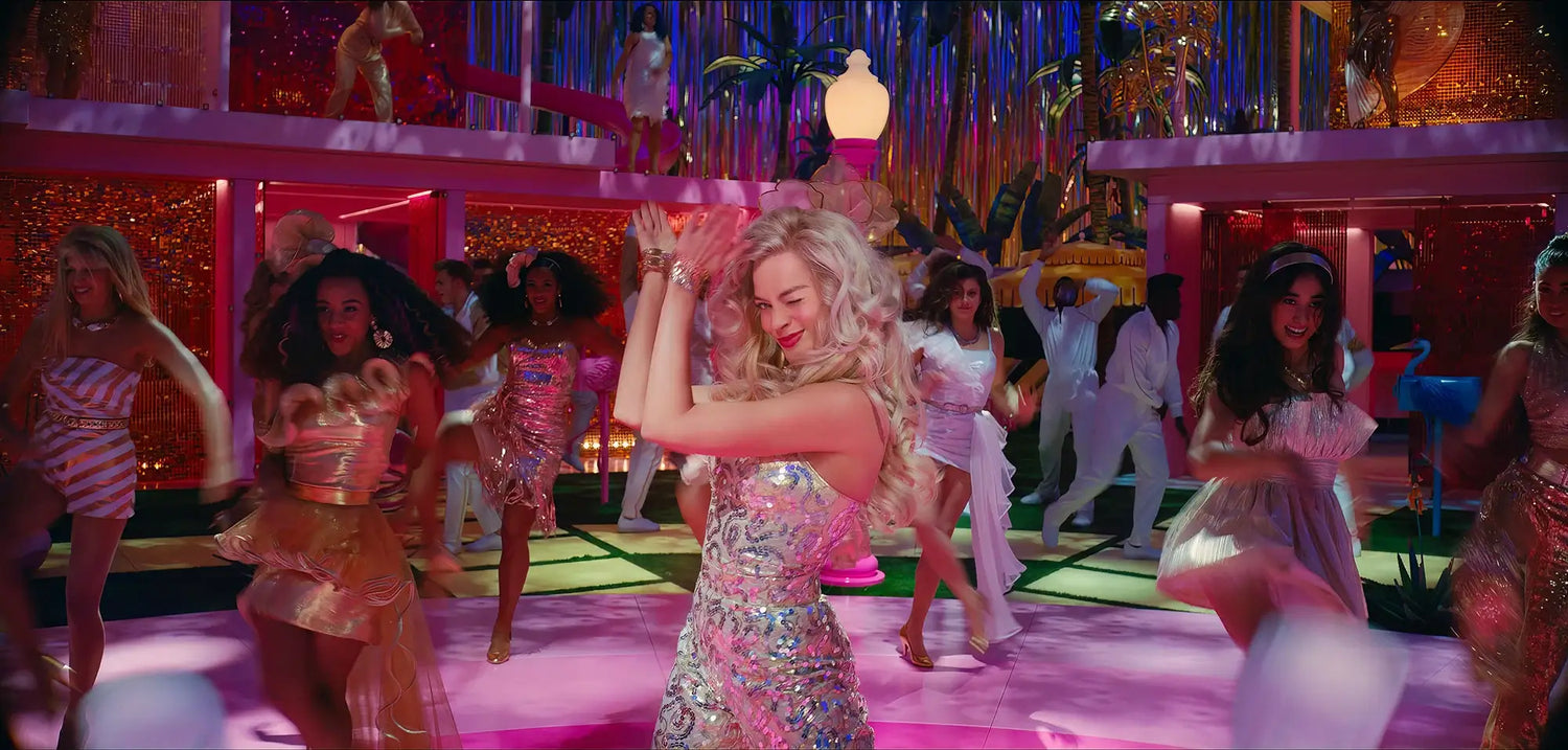 A picture of Margot Robbie as Barbie in a sequin jumpsuit and coordinating fascinator