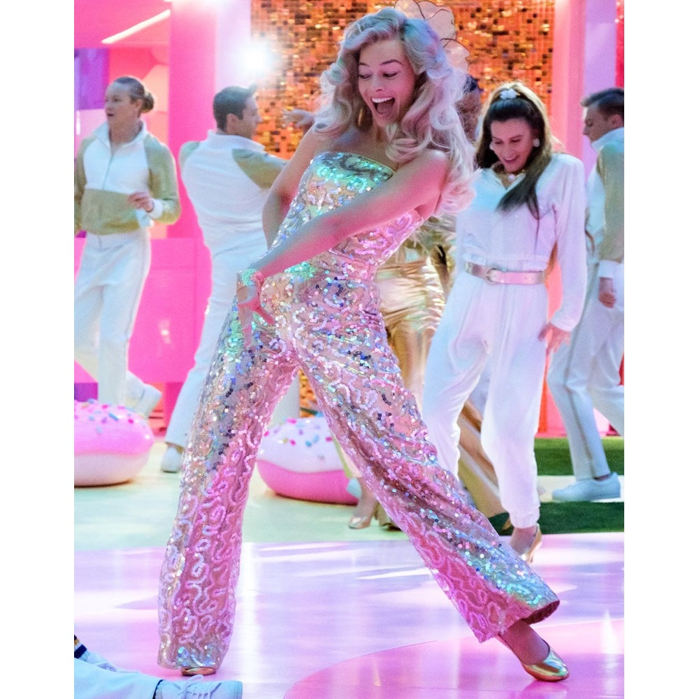 A picture of Margot Robbie as Barbie in a sequin jumpsuit, fascinator and gold shoes.