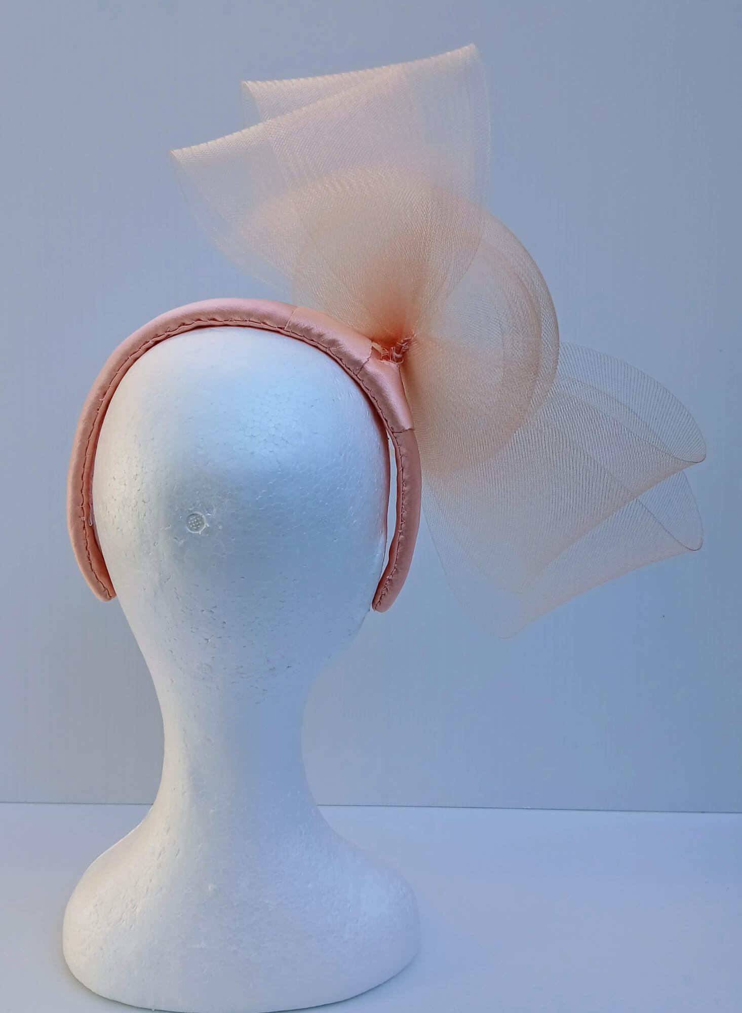 A picture  of an Apricot Crinoline Bow and Rose Headband by Melissa Rath Millinery.