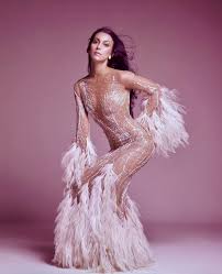 A picture of singer Cher posing in a photo shoot fro the December issue of Vogue in 1974  in a sequinned and feathered dress.