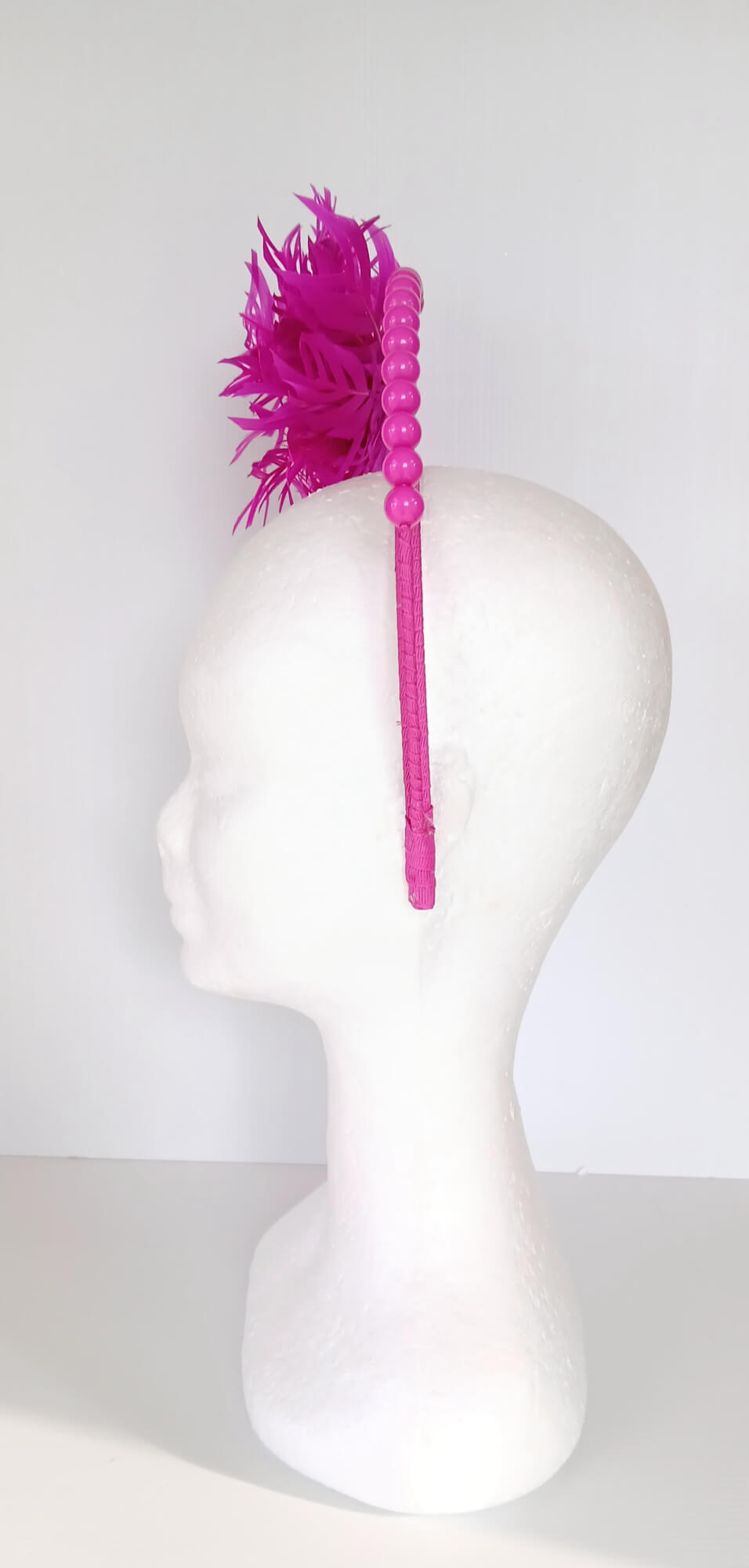 A picture of a Pink Halo Beaded Headband with feather flower by Melissa Rath Millinery.