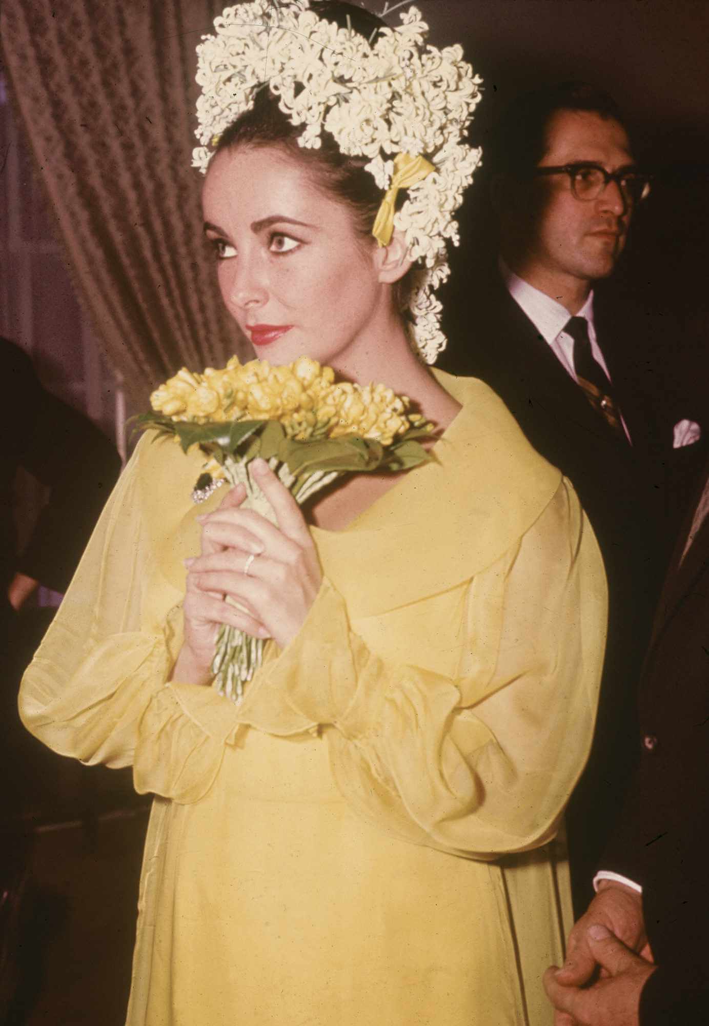 A picture of Elizabeth Taylor wearing a yellow outfit in her wedding to Richard Burton in 1964.