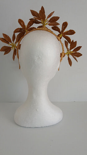 A picture of a gold feather flower headband by Melissa Rath Millinery.