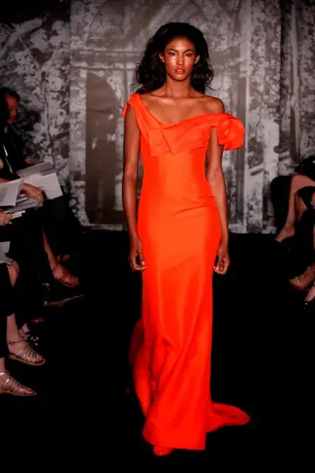 A picture of a model in a beautiful orange gown by Carolina Herrera.