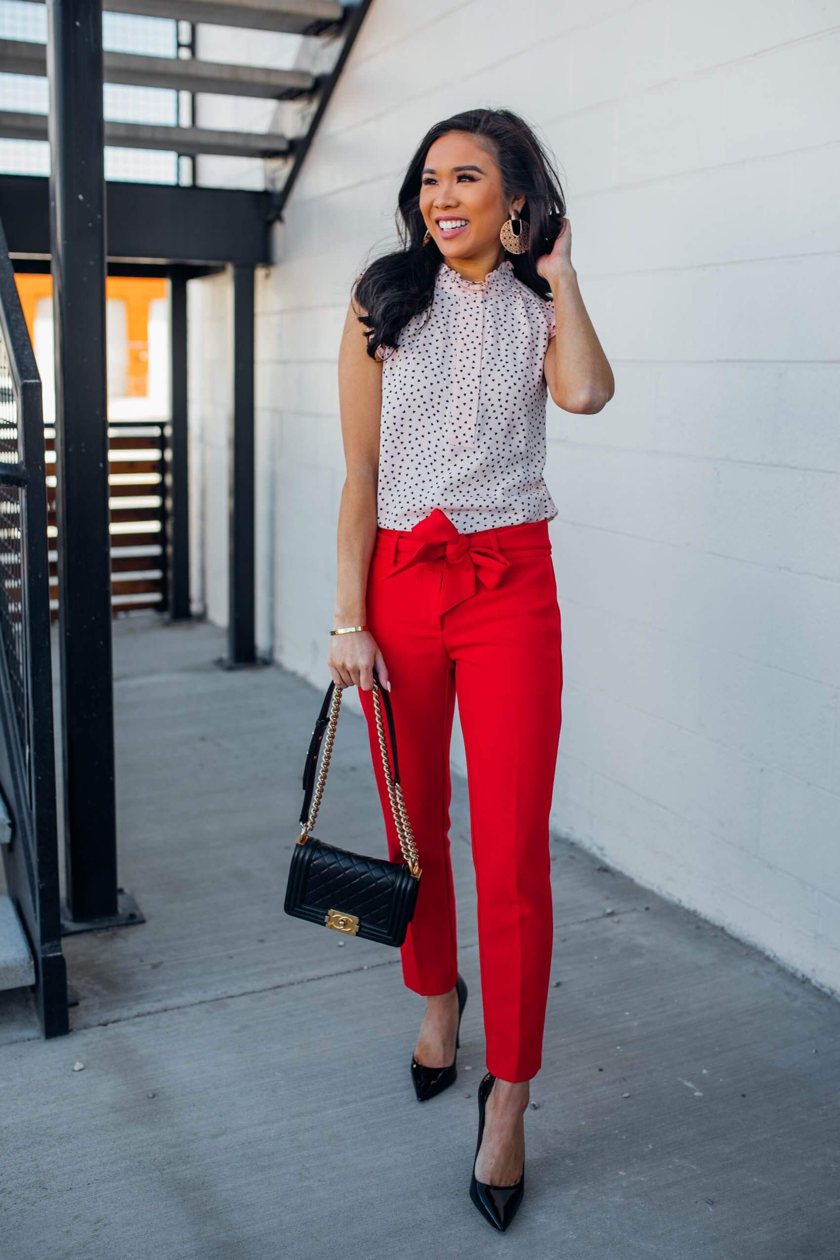 A picture of a woman wearing red pants with an otherwise neutral outfit, which adds colour to an otherwise neutral outfit.