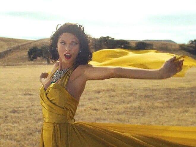 A picture of Taylor Swift in a stunning yellow chiffon h=gown in her Wildest Dreams video.