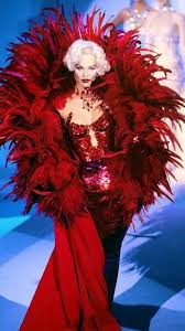 A model wearing an outfit adorned with feathers on the runway for Thierry Mulger in the 1990's