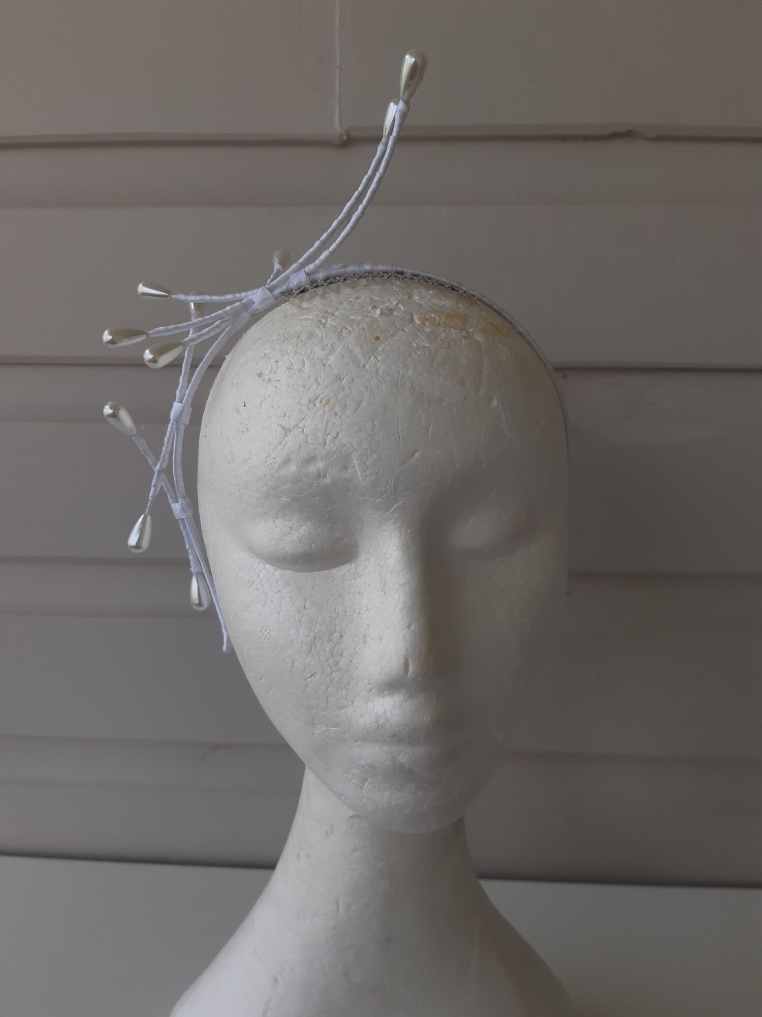 A picture of an Asymmetrical White Beaded Millinery Headband by Melissa Rath Millinery.