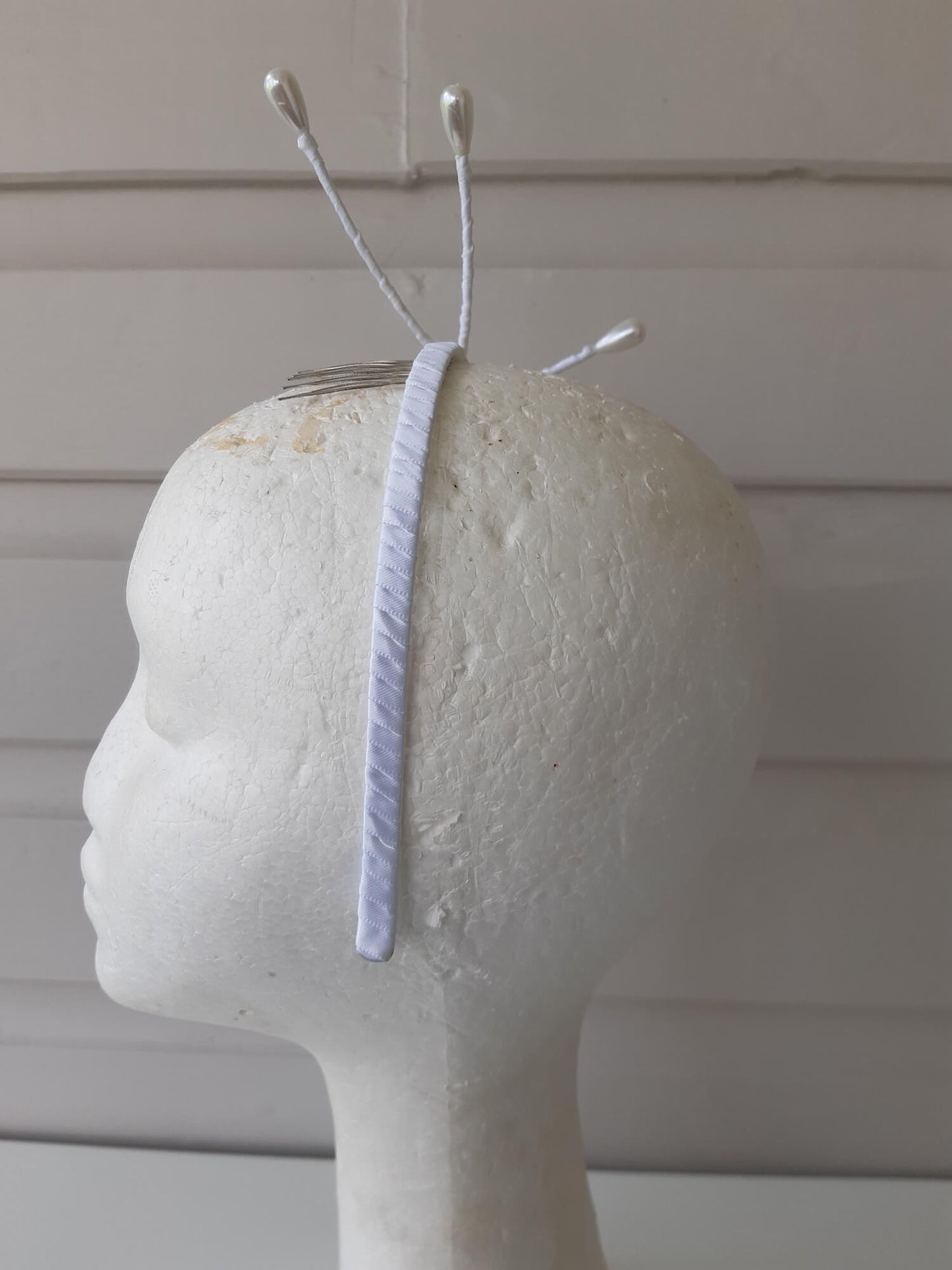 A picture of an Asymmetrical White Beaded Millinery Headband by Melissa Rath Millinery.