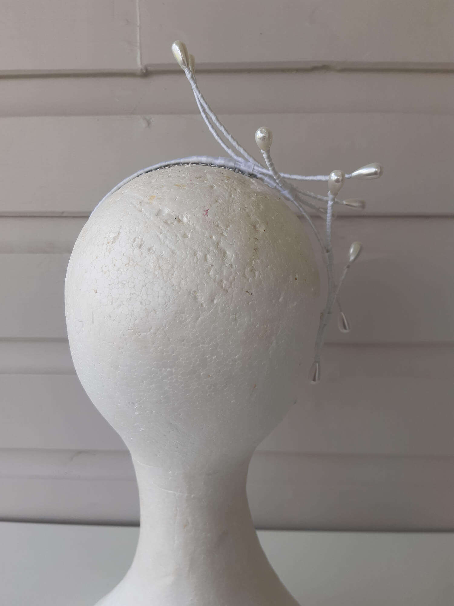 A picture of an Asymmetrical White Beaded Millinery Headband by Melissa Rath Millinery.