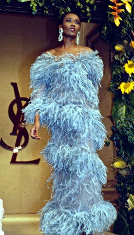 A picture of model Naomi Campbell wearing a blue feathered dress on the runway for YSL in the 1987-88 show