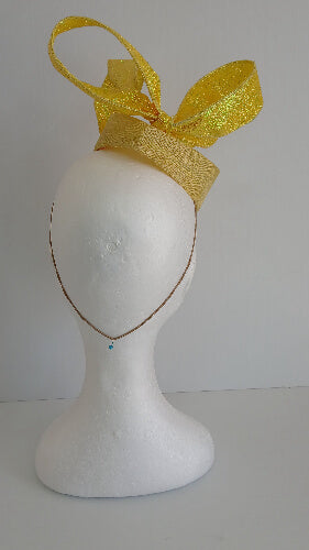 A picture of a yellow sinamay fascinator with a wired bow by Melissa Rath Millinery.