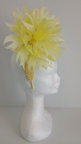 A picture of the yellow sinamay blocked crown with feather flower by Melissa Rath Millinery.